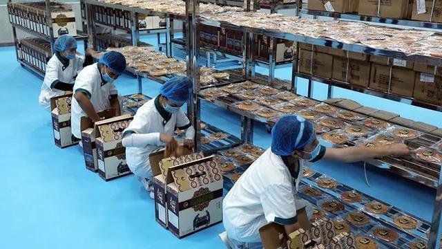 新疆霍尔果斯馕产业园内,工人将制作好的馕饼放入包装盒以供销售.